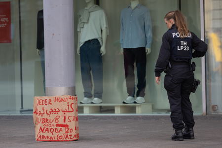 eine polizistin sieht ein plakat einer demonstration an