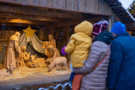 eine familie sieht eine holzgeschnitzte weihnachtskrippe an