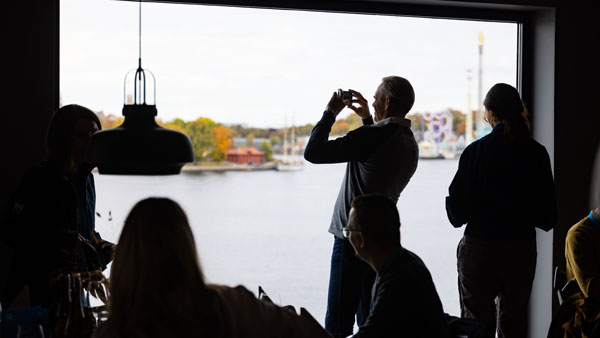 Silhouetten von Konferenzteilnehmenden, die den Ausblick auf das Wasser in Stockholm genießen, während eine Person ein Foto macht.