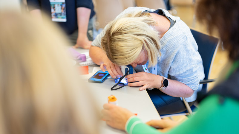 Eine Teilnehmerin benutzt eine Lupe und ein Smartphone, um einen Gegenstand während eines Workshops auf dem MINT-Fachtag im Augustinerkloster in Erfurt genauer zu betrachten.