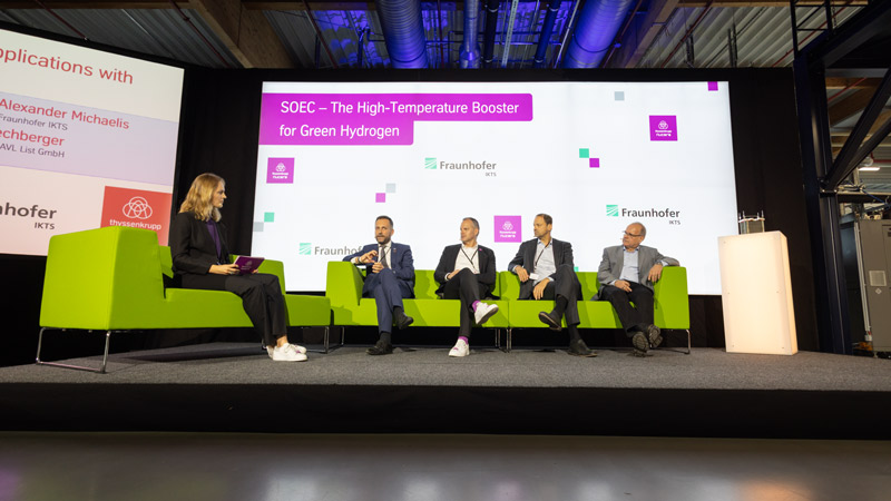 Podiumsdiskussion zum Thema „SOEC – Der Hochtemperatur-Booster für grünen Wasserstoff“ mit fünf Teilnehmenden auf einer Bühne.