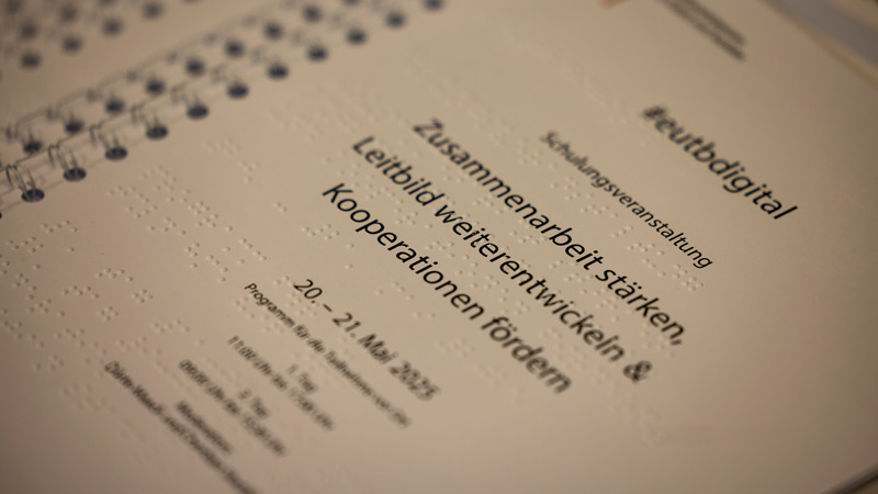Tagungsprogramm mit Brailleschrift; Titel: „Zusammenarbeit stärken, Leitbild weiterentwickeln & Kooperationen fördern“.