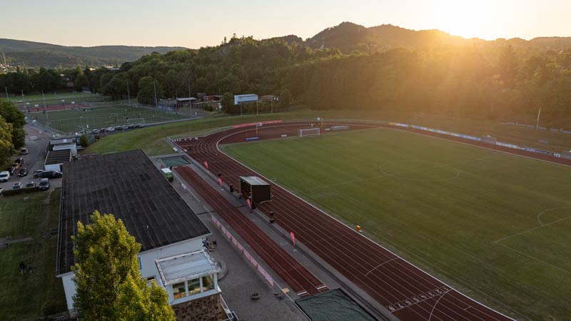Luftaufnahme eines Stadions mit Laufbahn bei Sonnenuntergang.