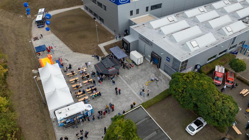 Luftaufnahme eines Firmenfests mit Essensständen, Zelten und Besuchern vor dem STAHL-Gebäude.
