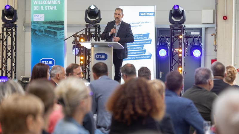 Mann hält Rede am Rednerpult bei STAHl-Veranstaltung mit Publikum im Vordergrund.