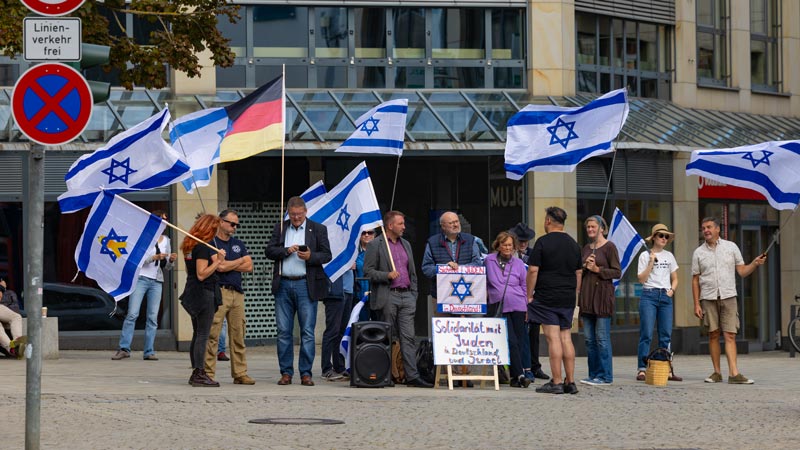 Gruppe mit israelischen und deutschen Fahnen bei einer pro-israelischen Kundgebung, mit Schild zur Solidarität mit Juden.