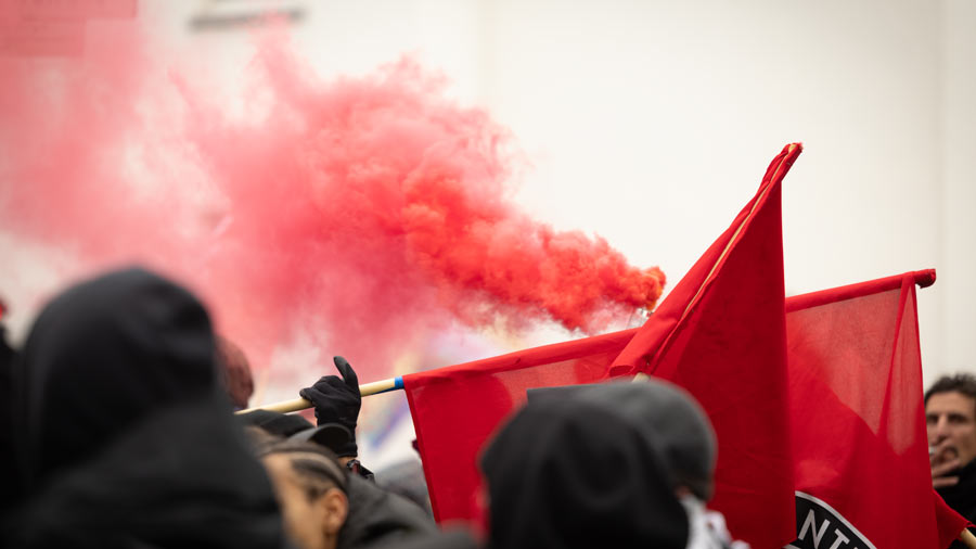 Rote Fahnen und roter Rauch bei einer Demonstration in Nahaufnahme