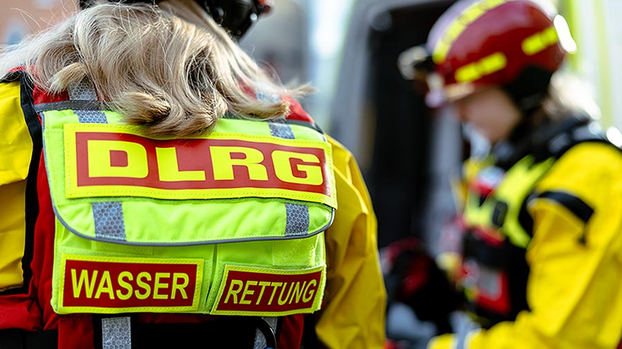 Rückansicht einer DLRG-Einsatzkraft mit reflektierender Weste „WASSERRETTUNG“.