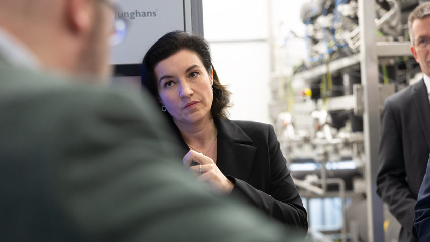 Dorothee Bär hört konzentriert einem Vortrag zu, im Hintergrund unscharf die Laboranlagen des Fraunhofer-Instituts Hermsdorf – Fotoreportage von Paul-Philipp Braun