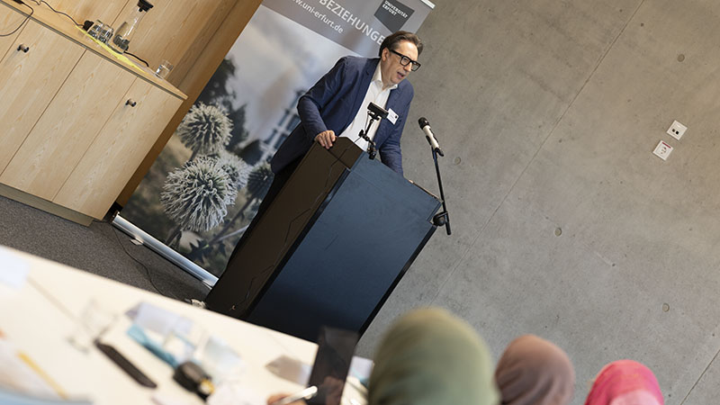 Vortragender am Rednerpult bei der internationalen Konferenz God Human Machine an der Universität Erfurt, Publikum im Vordergrund